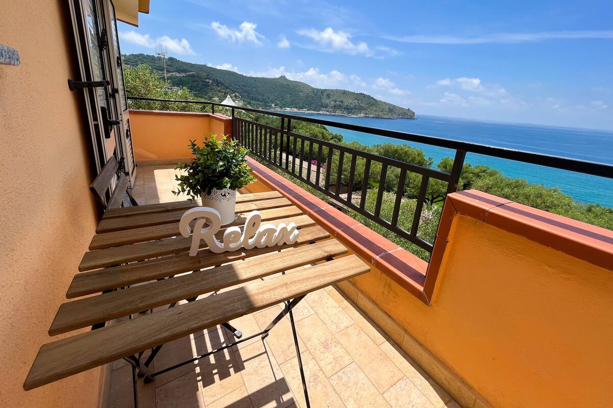 A balcony with a wooden bench, a potted plant, and a 'Relax' sign.