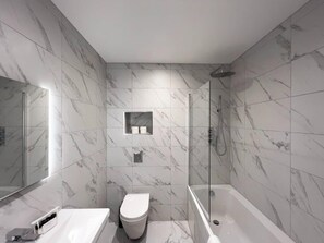 Une salle de bain moderne équipée d’une baignoire, de toilettes et d’une douche.