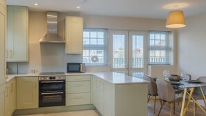 Une cuisine moderne dotée d’un îlot central, d’un four encastré et d’un coin repas avec une table et des chaises.