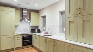 A modern kitchen with light green cabinets, stainless steel appliances, and a white countertop. - Modern 2 Bed Ground Floor - Parking - By Tempstay (Berkshire)