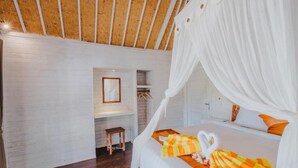 A bedroom with a canopy bed, wooden flooring, and a small bedside table. - Paluh Beach Huts (Lembongan Island)