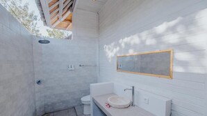 A modern bathroom with a built-in shower, a freestanding toilet, and a vanity with a round sink. - Paluh Beach Huts (Lembongan Island)