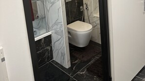A modern bathroom with a toilet, shower, and a mirror.