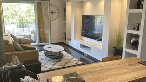 A modern living room with a wooden bar, a TV, and a seating area with a sofa and chairs.