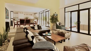 Un salón amplio con un sofá grande, una mesa de centro y una zona de comedor al fondo.