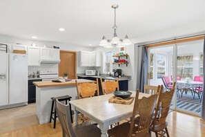 A modern kitchen with white cabinets, a wooden island, and a dining area with a table and chairs.