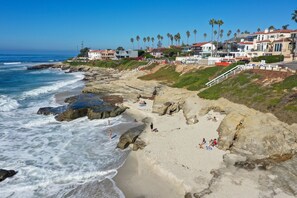A coastal beach with rocky terrain, palm trees, and beachfront houses. - Oceanfront Luxury Living in Windansea | AC | Outdoor Living (La Jolla)