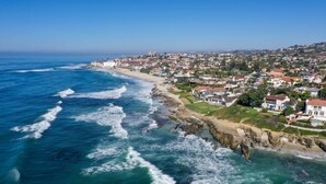 A coastal town with a beach, houses, and rocky cliffs.
