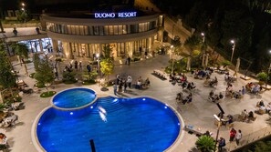 A resort with a large outdoor pool, outdoor dining areas, and a well-lit entrance. - Duomo Resort (Shkodër)