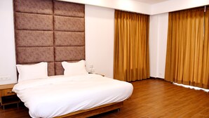 Une chambre moderne avec un grand lit, un plancher en bois et une tête de lit capitonnée.