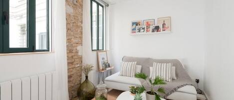A modern living room with a white sofa, a coffee table, and a brick wall.