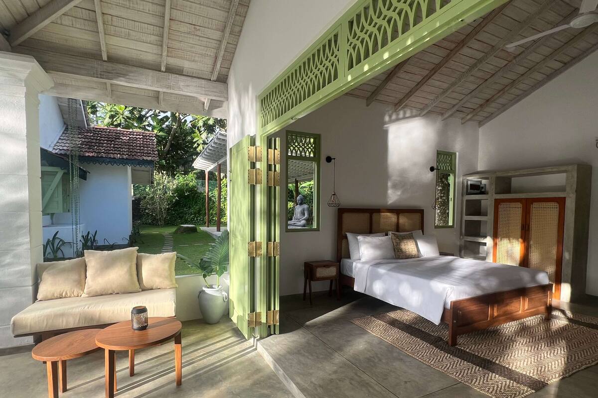 A bedroom with a bed, a sofa, a small table, and a green decorative screen.