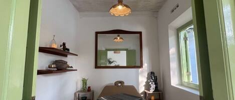 A room with a wooden table, a hanging light fixture, a mirror on the wall, and a window.