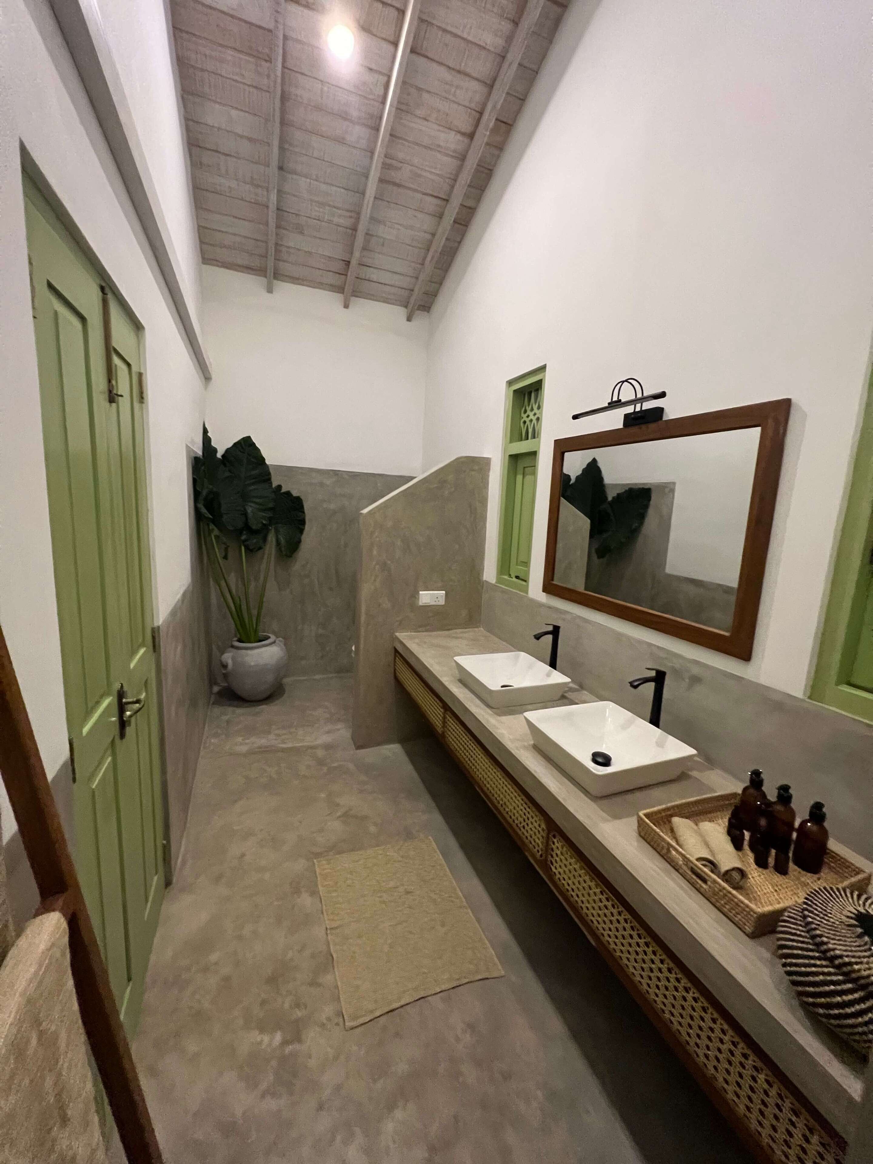 Een badkamer met twee wastafels, een grote spiegel en een potplant.