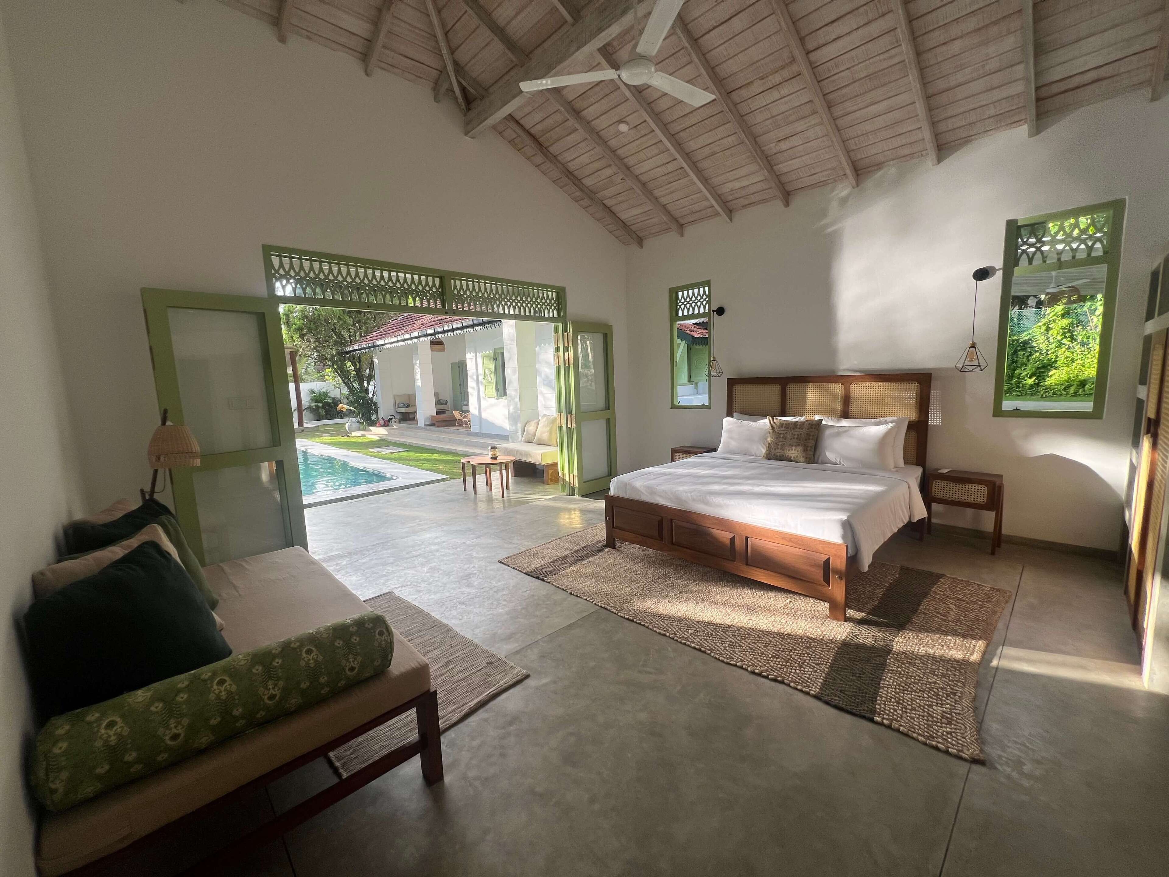 Un dormitorio con una cama grande, una zona de estar con sofá y vistas a un patio exterior.