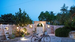A stone building with a door, a bicycle, and string lights.