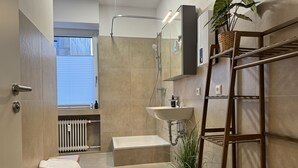 A modern bathroom with a shower, sink, and a wooden bench. - Dein Citynest - FeWo Meier (Bielefeld)