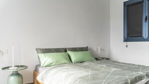A minimalist bedroom with a bed, two bedside tables, and a window with a blue frame. - SOL UNA Joya (CN)
