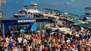A crowded outdoor event with a stage labeled "WATERFRONT" and numerous people gathered around. - Homesmith Cottage|Hot Tub| Walk to Buckeye Lake (Buckeye Lake)