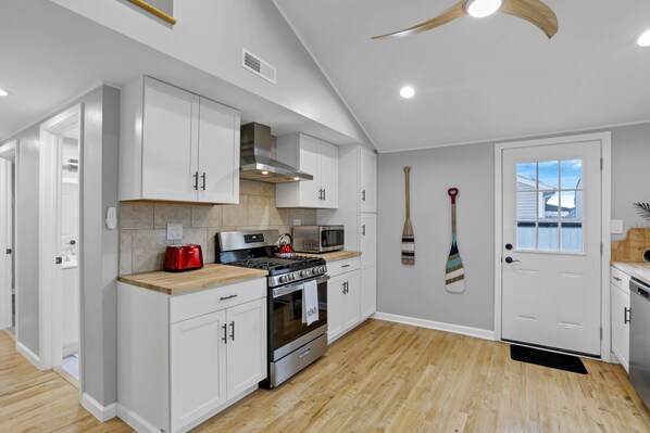 A modern kitchen with white cabinets, a stainless steel stove, and a microwave.