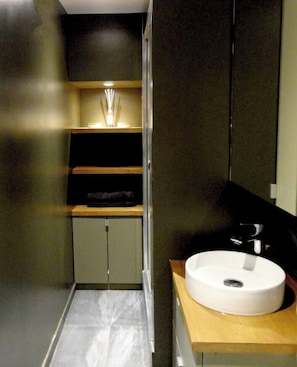 A modern bathroom with a white sink, a wooden countertop, and a mirror.