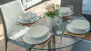 A dining table set with white plates, glasses, and cutlery, surrounded by grey chairs. - Skyvillion - River View Mins To O2 & London Excel (London)