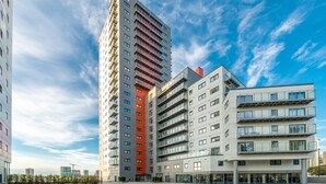 A modern high-rise building with multiple balconies and a flat roof. - Skyvillion - River View Mins To O2 & London Excel (London)