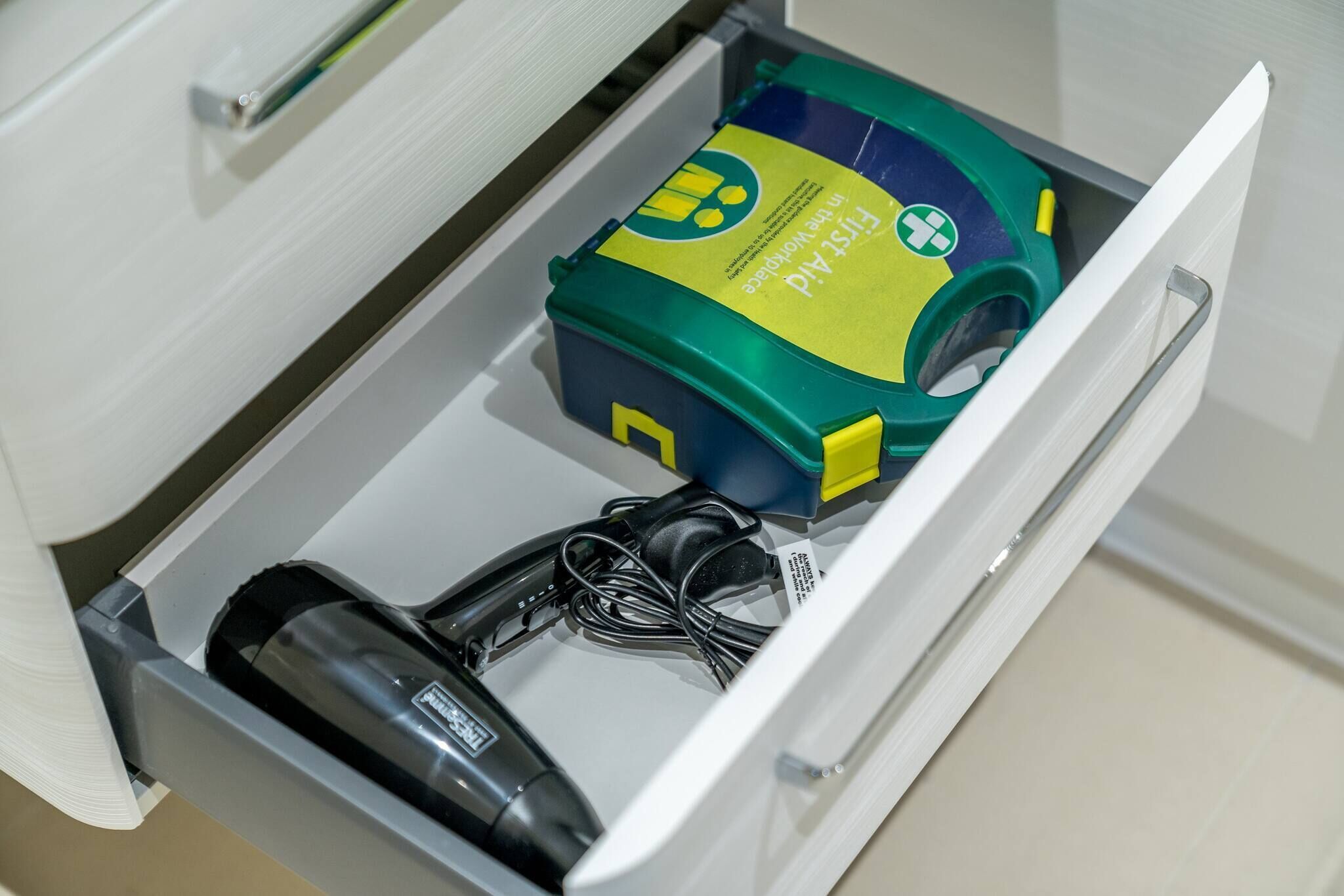 Un cajón con un dispositivo médico, un cable de alimentación y una caja con un logotipo.
