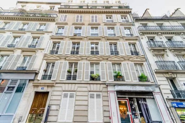 A multi-story building with a classic architectural style, featuring symmetrical windows and shutters.