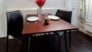 A dining table set with plates, cutlery, and a vase with red flowers. - Cocoon Rodier (Paris)