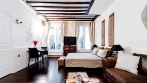 A modern bedroom with a bed, a brown leather sofa, a desk with a chair, and a TV. - Cocoon Rodier (Paris)
