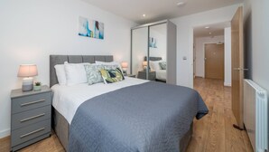 A bedroom with a bed, bedside tables, a wardrobe, and a painting on the wall.