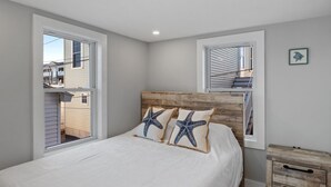 Une chambre à coucher avec une tête de lit en bois, deux fenêtres et une table de chevet.