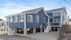 Une maison à deux étages avec un porche à l’avant et un escalier menant à l’entrée.