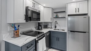Une cuisine moderne avec des armoires blanches, un réfrigérateur en acier inoxydable, une cuisinière et un four à micro-ondes.