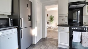 Een moderne keuken met roestvrijstalen apparatuur, witte kasten en uitzicht op de eetruimte.
