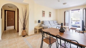 A dining area with a wooden table and chairs, a sofa, a small side table, and a vase with branches. - Wonderluxury Esuri (Ayamonte)