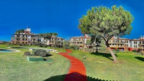 A hotel courtyard with a red pathway, a large tree, and multiple buildings in the background. - Wonderluxury Esuri (Ayamonte)