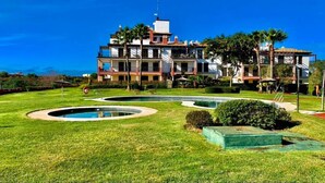 A large, multi-story hotel with a pool area featuring circular water features and well-maintained lawns. - Wonderluxury Esuri (Ayamonte)