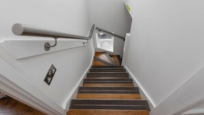 A staircase with a metal handrail, wooden steps, and a small window at the top. - Skyvillion - Central Ldn 3bed Flat Ladbroke Grove (London)