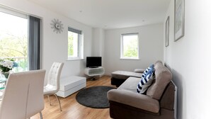 A modern living room with a sofa, a chair, a TV, and a small table.