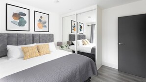 Una moderna camera d'albergo con un letto grande, uno specchio e un quadro astratto appeso alla parete.