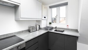 Una cocina moderna con placa de inducción integrada, un tostador, un hervidor y un lavabo.