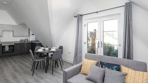 Un apartamento moderno con comedor, kitchenette y balcón con cortinas.