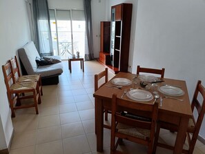 A dining area with a wooden table set for four, surrounded by wooden chairs.