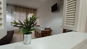 A dining area with a table and chairs, a potted plant, and a ceiling light.