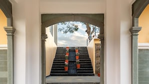 A grand entrance with a stone staircase, a circular floor design, and a view of the outside. - Jhadol Bagh (Jharol)
