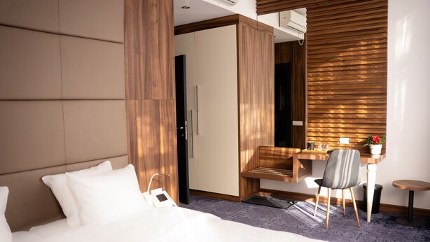 A hotel room with a bed, a desk, a chair, and a wardrobe. - Olivia Rooms (Belgrade)