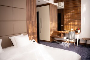 Een hotelkamer met een bed, bureau, stoel en garderobe.