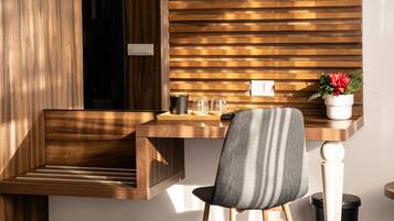 Een moderne kamer met een houten bureau, een stoel, een kleine plant in pot en een prullenbak.